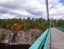 Suspension bridge walkway in Ontario, Canada. Large pedestrian and snowmobile bridge that crosses the French river in French River Provincial Park, Killarney.